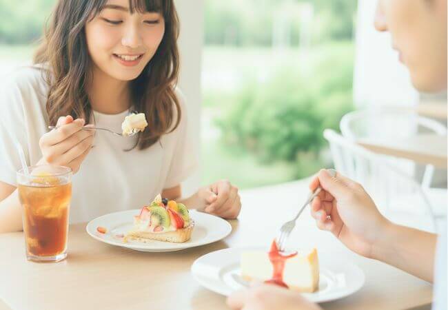 カフェデートでケーキを食べながら楽しく話をする婚活中の男女のイメージ画像です。
