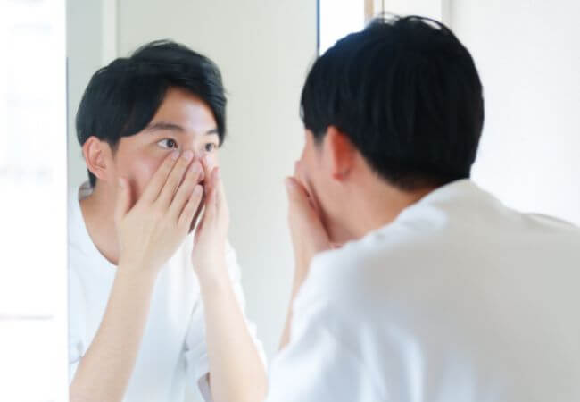 婚活のために鏡を見て身だしなみを整える男性のイメージ画像です。