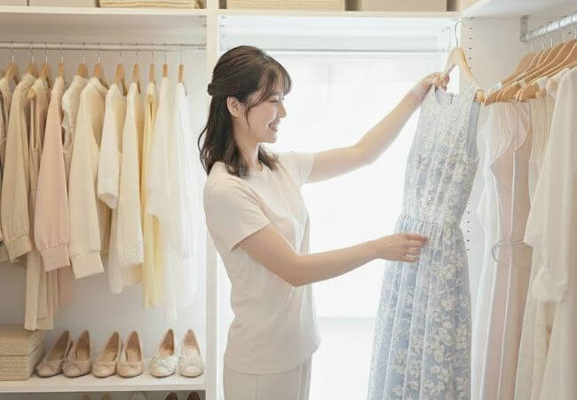 婚活写真で着るためのワンピースを選んでいる女性のイメージ画像です。